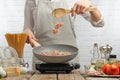 Chef fries bacon, meat in a frying pan on the background of a light kitchen. Culinary recipes, cooking Royalty Free Stock Photo