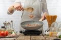 Chef fries bacon, meat in a frying pan on the background of a light kitchen. Culinary recipes, cooking Royalty Free Stock Photo