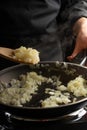 Chef fries onions in a pan for cooking. Restaurant and hotel business, recipe book, menu