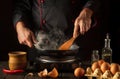 The chef is frying eggs in a frying pan. Cooking an omelette with egg in the kitchen. Menu or recipe idea for a hotel Royalty Free Stock Photo