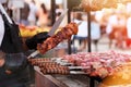 Chef frying meat on grill. Cook in black apron fries meat on fire. Barbecue in open air. Bright sunlight bokeh Royalty Free Stock Photo