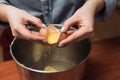 Chef girl breaks eggs in a bowl for dough. Adding egg yolk to cooking. The man breaks the egg into a metal bowl.