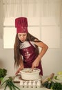 chef girl in hat and apron. kid cooking food in kitchen. choosing a career. little helper baking. culinary and cuisine Royalty Free Stock Photo