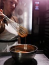 chef girl whips melted chocolate in a bowl with an old metal wire whiskey close-up on her hand and dishes Royalty Free Stock Photo