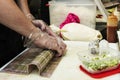 A chef with gloved hands making sushi rolls with Japanese rice, raw escado and vegetables Royalty Free Stock Photo