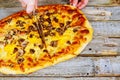 Chef in gloves cutting hot ready pizza by rolling pizza cutter, closeup