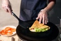 Chef making stuffed crepe, roll up crepe on hot cooktop. Traditional restaurant cooking concept. Detailed. Front view.