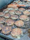 Chef grilling appetising beef burgers and bratwurst outdoors Royalty Free Stock Photo
