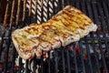 Chef grilling a beef steak on open flame BBQ.