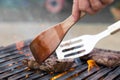 Chef grilling beef steaks on open flame BBQ.