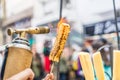 A chef grilling cheese with a kitchen gas torch at a food market.