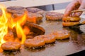 Chef grilling fresh spiral pork sausages on brazier with hot flame