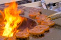 Chef grilling fresh spiral pork sausages on brazier with hot flame