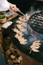The chef grills the squid on wooden skewers.