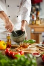 Chef grinding fresh herbs in a pestle and mortar Royalty Free Stock Photo