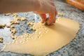 A hand making shapes in an extended dough on a kitchen table making seasonal pastry food.