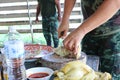 Chef hand, male soldier Is using a knife to cut chicken meat on a wooden chopping board, Thai food