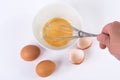 Chef hand with whisk and whipped eggs in bowl on white kitchen table Royalty Free Stock Photo