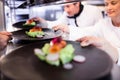 Chef handing appetizer plate through order station