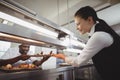 Chef handing food dish to waitress at order station