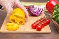 Chef hands in cellophane gloves cutting yellow pepper paprika and different vegetables for salad close up Royalty Free Stock Photo