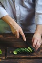 Chef hands cut a cucumber with a knife on a cutting board Royalty Free Stock Photo