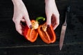 Chef hands cut red bell pepper on black wooden background. Royalty Free Stock Photo