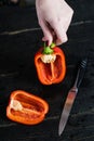 Chef hands cut red bell pepper on black wooden background. Royalty Free Stock Photo