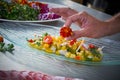 Chef hands garnishing flower in ceviche dish