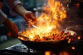 Chef hands keep wok with fire. Closeup chef hands cook food with fire. Chef man burn food at professional kitchen