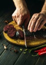 Chef hands with a knife cut blood sausage on a kitchen cutting board. Cooking a national dish with spices and pepper at home in Royalty Free Stock Photo