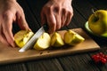 Chef hands with a knife cut fresh apples on a wooden cutting board. Apple diet idea Royalty Free Stock Photo
