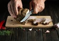 Chef hands with a knife cut grilled veal meat into small slices. Work environment on the kitchen table with condiments or spices. Royalty Free Stock Photo