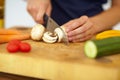 Chef hands, knife and vegetables on chopping board, cooking and preparation at home. Closeup of woman cutting mushrooms