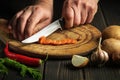 Chef hands with a knife while working on the kitchen table. Slicing carrots on a wooden board for food Royalty Free Stock Photo