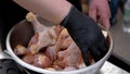 Chef hands marinate raw chicken legs.