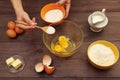 Chef hands pour sugar into a bowl for making dough on wooden table Royalty Free Stock Photo