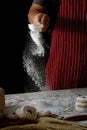 Chef hands sprinkling preparing bread dough and doughnuts with icing sugar on wooden table isolated on black background