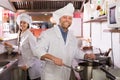 Chef and his helper at bistro kitchen Royalty Free Stock Photo