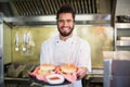 Chef holding burgers in plate at commercial kitchen Royalty Free Stock Photo