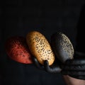 Chef holding different types of bread. Hand in black glove demonstrates red, white and rye loaf of bread with sesame Royalty Free Stock Photo