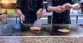 Chef holding meat on spatula. Ground beef patty on grill