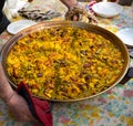 Chef holding a paella pan with a freshly cooked authentic Valencian paella,