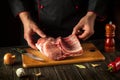 The chef is holding a piece of raw meat with a bone in the kitchen. Pork ribs in the butcher hands. European cuisine