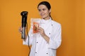 Chef holding sous vide cooker and salmon in vacuum pack on orange background