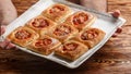 Chef holding a tray of pies of puff pastry with tomatoes