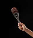 Chef holding wire whisk and melted chocolate on black background Royalty Free Stock Photo