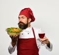 Chef holds bowl with potato casserole and glass of alcohol.