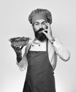 Chef holds bowl with potato casserole showing Super Tasty sign. Cook with happy face in burgundy uniform holds baked Royalty Free Stock Photo