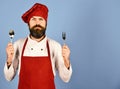 Chef holds cutlery. Cook with serious face in burgundy uniform Royalty Free Stock Photo